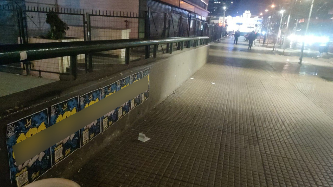 Row of branded posters placed along a busy pedestrian corridor in central Santiago